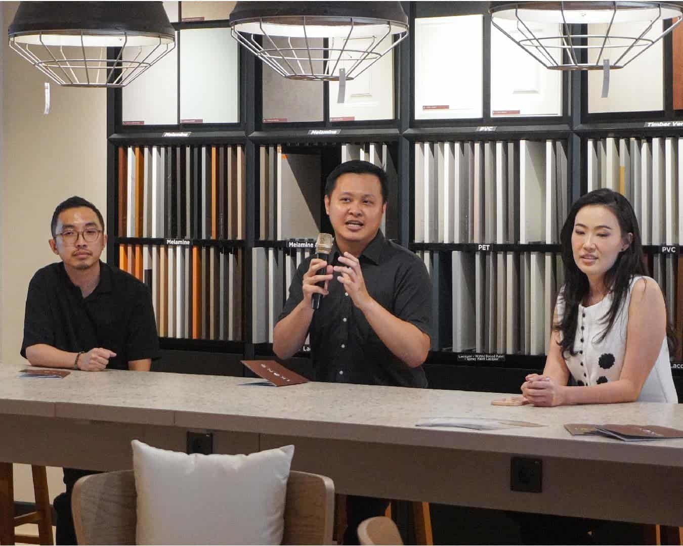 Panel Discussion: Three presenters at a counter in front of fabric swatches, smiling and engaged.