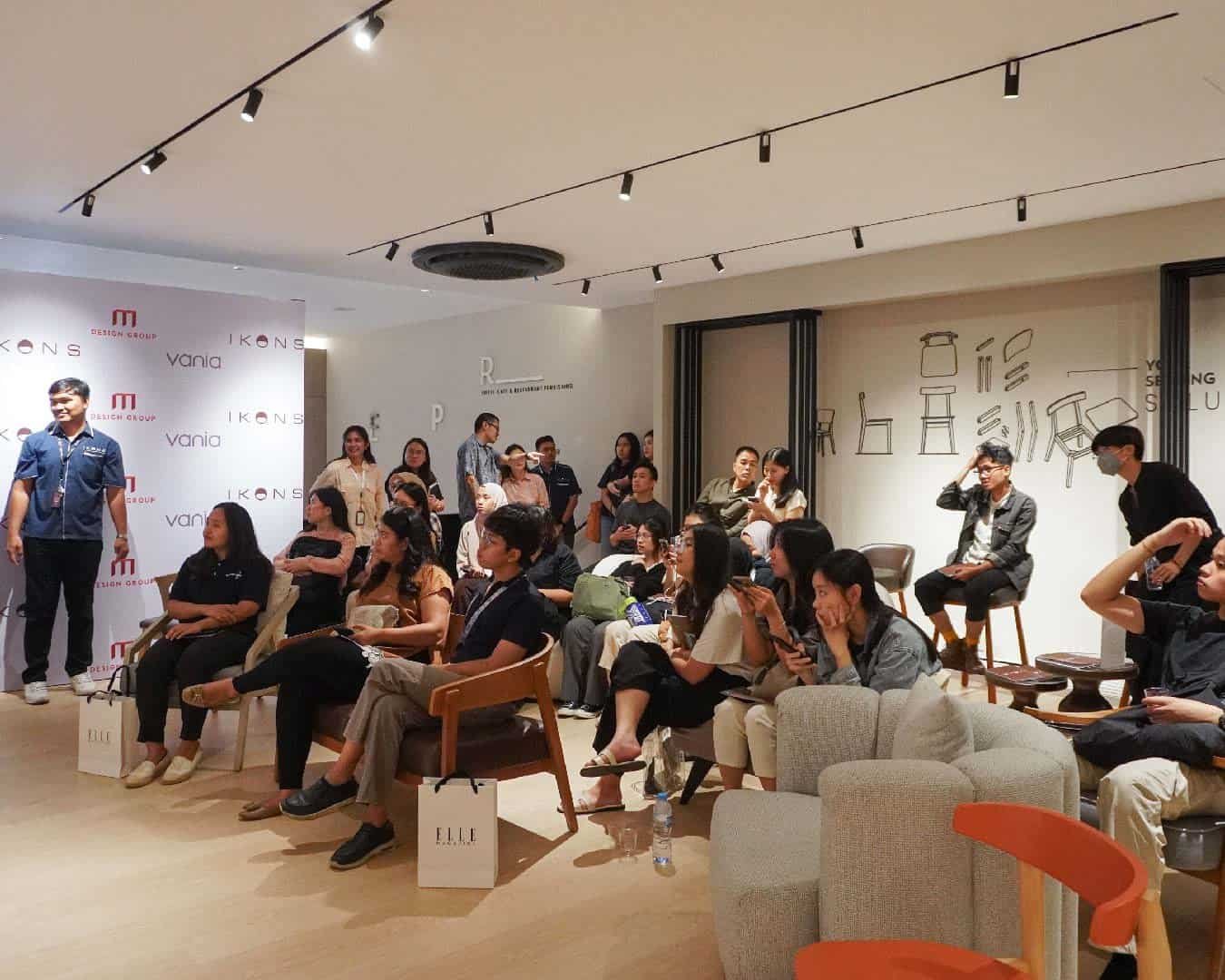 Event Audience: Attendees seated and attentively watching the presentation in a well-lit modern interior.